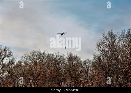 Eine Crew der Nationalgarde der Wisconsin Army UH-60 Black Hawk mit dem 1. Bataillon in Madison, Wisconsin, 147. Aviation Regiment-Zug, der am 28. März 2022 mit Bambi-Eimern in Fort McCoy, Wisconsin, Wasser auf Waldbrände wirft. Mitarbeiter der Feuerwehr von Fort McCoy, der Direktion für öffentliche Arbeiten, natürliche Ressourcen, der Wisconsin Abteilung für natürliche Ressourcen und Flugbesatzung sowie Black Hawk Helikopter des 1. Bataillons, 147. Luftfahrtregiment in Madison, Wisconsin, nahmen an der Feuerschulung während einer vorgeschriebenen Brandverbrennung Teil. Stockfoto