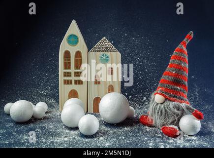 Weihnachtsdekoration Elf, Zwerg, der Schneeball vor dem Gebäude hält. Winterfestival-Konzept, Hintergrundszene für Feiertage Stockfoto