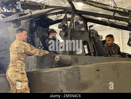 Oberbefehlshaber 2 Brinton Mitchell, ein AH-64-Apache-Pilot, der Alpha-Truppe zugeteilt wurde, 6. Luftkavallerie-Geschwader, 17. Kavallerie-Regiment, 4. Kampfluftfahrt-Brigade, 4. Infanterie-Division, zeigt Schülern mit der Carson Middle School in Fort Carson, Colorado, 28. März 2022 das Innere des Apache-Hubschraubers. Der Apache AH-64D/E ist der Angriffshubschrauber der Armee. Es ist in der Lage, Panzer, Personal und materielle Ziele unter verdeckten Schlachtfeldbedingungen zu zerstören. Stockfoto