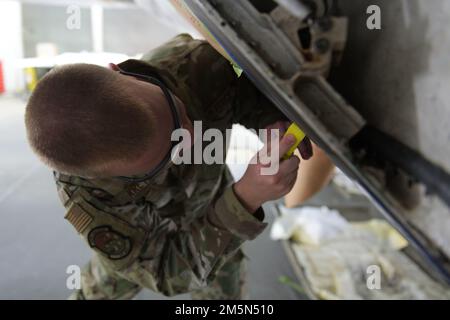 USA Air Force Senior Airman William Kretzer, 325. Wartungsgeschwader, niedrig, beobachtbarer Reisender, kratzt Farbe von einem F-22 Raptor auf dem Luftwaffenstützpunkt Tyndall, Florida, 28. März 2022. Die LO Airmen von Tyndall warten und reparieren die Außenstruktur von F-22s, die dem 325. Kampfflug zugewiesen ist. Stockfoto