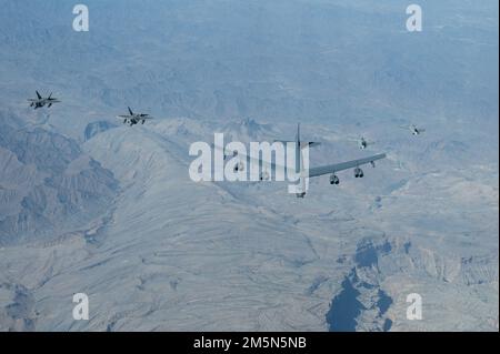 USA Air Force F-22 Raptors, links, und Royal Air Force von Oman Eurofighter Taifunen, rechts, fliegen neben einem US-amerikanischen Air Force B-52H Stratofortress, Zentrum, über Oman, 29. März 2022. Der Flug des Bombers begann in Royal Air Force Fairford, England, und flog über das östliche Mittelmeer, die Arabische Halbinsel und das Rote Meer, bevor er die Region verließ. Stockfoto