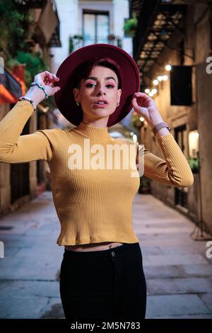 Stilvolle Frau mit Hut, die draußen in die Kamera schaut Stockfoto