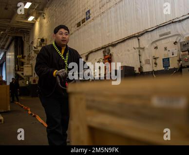 Aviation Boatswain's Mate (Handling) 1. Class Sherwin Buquid, aus Cam-Sur, Philippinen, zugewiesen zur Flugabteilung der USS Gerald R. Ford (CVN 78), verschiebt Fracht in der Hangarbucht, 29. März 2022. Ford führt im Atlantik im Rahmen der auf das Schiff zugeschnittenen Grundphase vor dem Einsatz die Zertifizierung von Cockpits und die Qualifizierung von Flugzeugflügelfluggesellschaften durch. Stockfoto