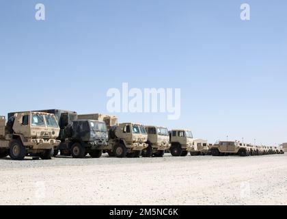 Militärfahrzeuge, die 3. Expeditionary Sustainment Command zugewiesen sind, werden auf einem leeren Parkplatz im Lager Arifjan, Kuwait, am 29. März 2022, abgestellt, wo sie auf den Transport zu einem Hafen warten. „Spears Ready“-Soldaten bereiten die Ausrüstung für den Versand zurück zu ihrer Heimatstation in Fort Bragg, N.C. vor Sie wurden seit August 2021 eingesetzt und besetzen den operativen Kommandoposten des 1. Theatre Sustainment Command. Stockfoto