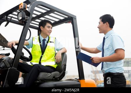 Das Management des Logistiklagers spricht mit dem Fahrer eines Gabelstaplers Stockfoto