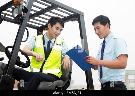 Das Management des Logistiklagers spricht mit dem Fahrer eines Gabelstaplers Stockfoto