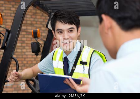 Das Management des Logistiklagers spricht mit dem Fahrer eines Gabelstaplers Stockfoto