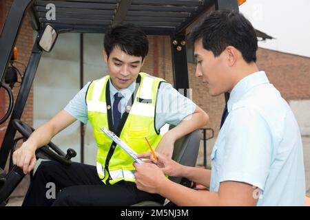 Das Management des Logistiklagers spricht mit dem Fahrer eines Gabelstaplers Stockfoto