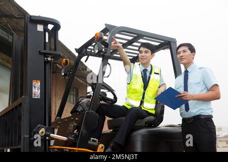 Das Management des Logistiklagers spricht mit dem Fahrer eines Gabelstaplers Stockfoto