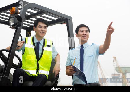 Das Management des Logistiklagers spricht mit dem Fahrer eines Gabelstaplers Stockfoto