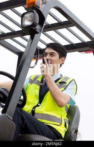 Logistikarbeiter, die Gabelstapler fahren, Handsprechanlage Stockfoto