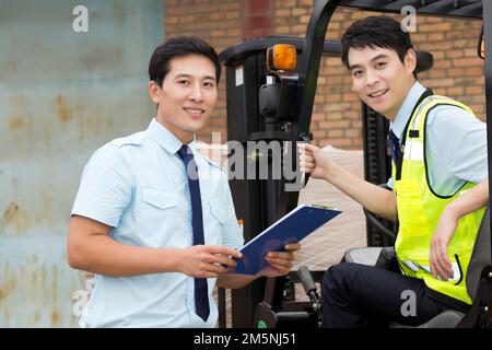 Das Management des Logistiklagers spricht mit dem Fahrer eines Gabelstaplers Stockfoto