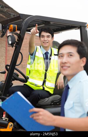 Das Management des Logistiklagers spricht mit dem Fahrer eines Gabelstaplers Stockfoto