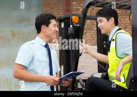 Das Management des Logistiklagers spricht mit dem Fahrer eines Gabelstaplers Stockfoto