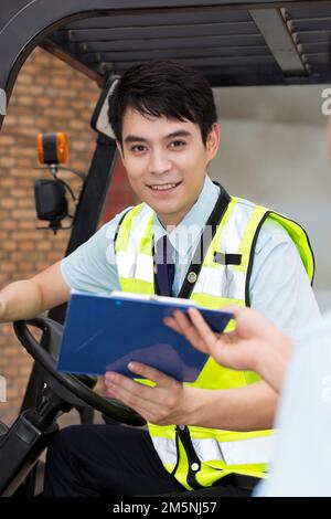 Das Management des Logistiklagers spricht mit dem Fahrer eines Gabelstaplers Stockfoto