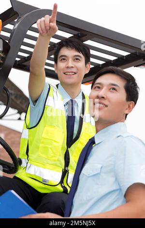 Das Management des Logistiklagers spricht mit dem Fahrer eines Gabelstaplers Stockfoto