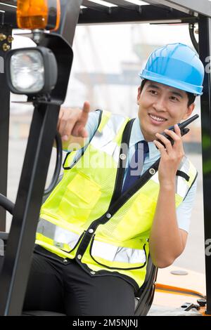 Logistikarbeiter, die Gabelstapler fahren, Handsprechanlage Stockfoto