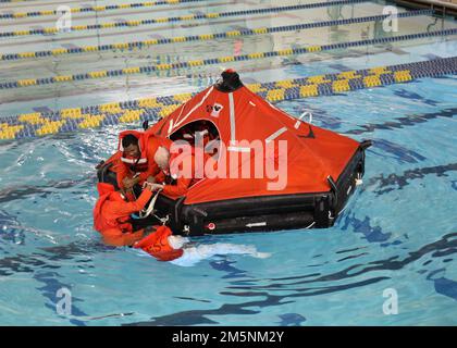 220225-N-OH262-0925--FORT EUSTIS, VA (25. Februar 2022)--neu eingestellte Military Sealift Command Civil Service Mariners (CIVMAR) üben das Einsteigen in ein aufblasbares Rettungsfloß im Military Sealift Command Training Center East auf der Joint Base Langley-Fort Eustis, Virginia, Februar 25. Die Fortbildung war Teil des Abschnitts „Sicherheit und Überleben“ des Lehrplans für die Grundausbildung des militärischen Sealift-Kommandos, der von allen MSC CIVMARs abgeschlossen werden muss, bevor sie der Flotte beitreten. Stockfoto