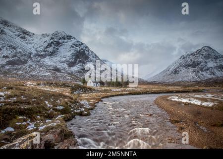 Old Cottage in den schottischen Highlands nahe Glencoe an einem Wintertag mit Schnee und Bergen von Schottland Stockfoto