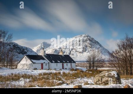 Old Cottage in den schottischen Highlands nahe Glencoe an einem Wintertag mit Schnee und Bergen von Schottland Stockfoto