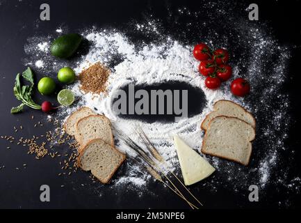 Brotscheiben, verstreutes Mehl auf schwarzem Hintergrund Stockfoto
