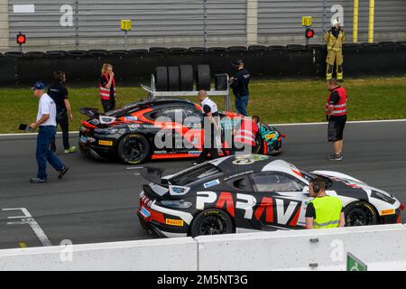 Zwei Rennsportwagen im Hintergrund Mechanics bereiten den Porsche Cayman GT4 Clubsport vor und starten das GTC-Rennen der GT4-Rennserie auf der Rennspur Stockfoto