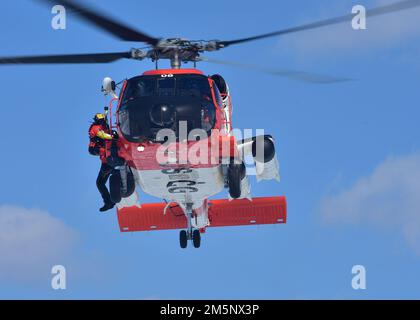Petty Officer 3. Class James Lowen, ein Rettungsschwimmer der Air Station Traverse City, bereitet sich darauf vor, einen simulierten Überlebenden während einer Masseneisrettungsübung am 26. Februar 2022 in der Petoskey Municipal Marina in einen MH-60 Jayhawk zu überführen. Die Übung, bei der der Absturz eines Pendlerflugzeugs in der Little Traverse Bay simuliert wurde, zog mehr als 100 Ersthelfer und Küstenwache-Mitglieder aus dem gesamten Norden von Michigan an. Foto der US-Küstenwache vom Chief Petty Officer John Masson. Stockfoto