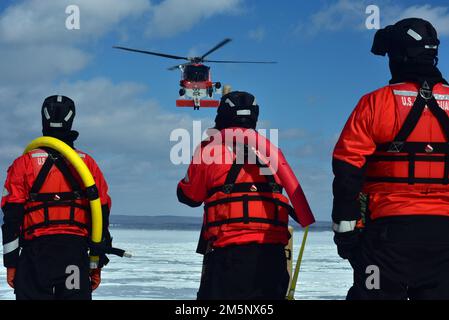 Ein MH-60 Jayhawk von der Air Station Traverse City bereitet sich darauf vor, einen Rettungsschwimmer während einer massiven Eisrettungsübung am 26. Februar 2022 in der städtischen Marina von Petoskey auf das Eis zu senken. Die Übung, bei der der Absturz eines Pendlerflugzeugs auf dem gefrorenen Lake Michigan simuliert wurde, brachte mehr als 100 Ersthelfer und Mitglieder der Küstenwache aus dem gesamten Norden von Michigan zusammen. Foto der US-Küstenwache vom Chief Petty Officer John Masson. Stockfoto
