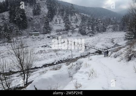 Srinagar, Indien. 30. Dezember 2022. Die Dorfbewohner wandern auf der schneebedeckten Brücke nach dem frischen Schneefall in Tangmarg, rund 40 kilim nördlich von Srinagar, der Sommerhauptstadt des Indischen Kaschmirs. Höhere Bereiche von Kaschmir erlebten leichten bis mittelschweren Schneefall und leichte Regenflächen. Der Zauber hat den Kreislauf intensiver kalter Wellen in der Region durchbrochen. (Foto: Sajad Hameed/Pacific Press) Kredit: Pacific Press Media Production Corp./Alamy Live News Stockfoto