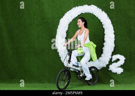 Die graskreativen jungen Frauen fahren Fahrrad Stockfoto