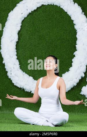 Die graskreativen jungen Frauen, die auf dem Gras sitzen Stockfoto