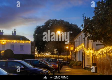 The Bury, ein Dorfplatz in Odiham, Hampshire, dekoriert mit Weihnachtslichtern in der Abenddämmerung im Dezember, England, Großbritannien Stockfoto