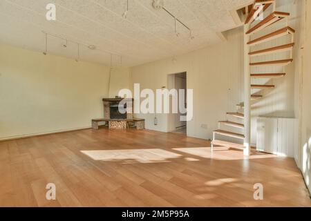 Ein leeres Wohnzimmer mit Holzfußboden und Treppe, die in den zweiten Stock dieses Hauses führt, gibt es einen Kamin Stockfoto