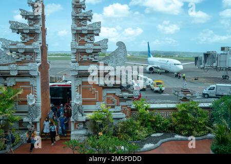 Badung, Bali, Indonesien, Okt. 6 2020: Flugpassagiere von Garuda Indonesia passieren das Ankunftstor in Form eines balinesischen Tores mit einem geparkten A. Stockfoto