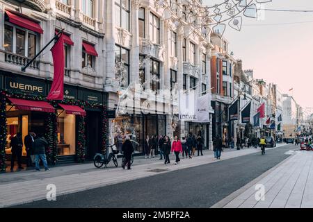 London, Großbritannien - 26. Dezember 2022: Die Leute gehen vorbei an den High-End-Geschäften auf der New Bond Street, einer der berühmtesten Straßen für Luxuseinkäufe in Lond Stockfoto