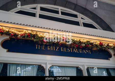 London, Großbritannien - 26. Dezember 2022: Festlich dekoriertes Schild vor dem Ritz Restaurant, gehobenes britisch-französisches Dining im barocken goldenen Salon mit Stockfoto