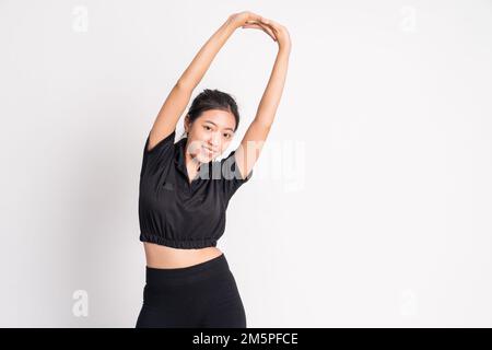 Frau trägt schwarze Sportbekleidung und streckt die Hände auf dem isolierten Hintergrund Stockfoto