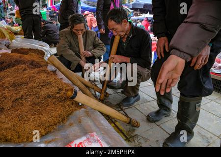 BAC Ha, Vietnam - 18. Dezember 2022: Männer, die auf dem Wochenmarkt von Bac Ha in Vietnam Tabak rauchen. Stockfoto