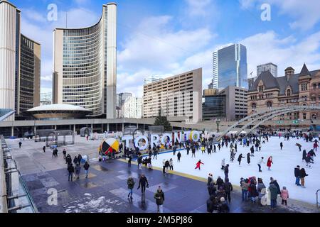 Toronto, Kanada - 2022. Dezember: Die kostenlose Eislaufbahn am Rathausplatz ist eine beliebte Attraktion. Skateboarden können ausgeliehen werden. Stockfoto