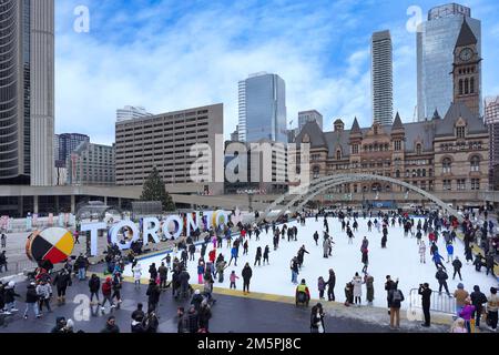 Toronto, Kanada - 2022. Dezember: Die kostenlose Eislaufbahn am Rathausplatz ist eine beliebte Attraktion. Skateboarden können ausgeliehen werden. Stockfoto