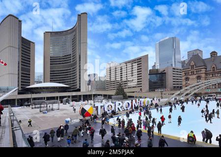 Toronto, Kanada - 2022. Dezember: Die kostenlose Eislaufbahn am Rathausplatz ist eine beliebte Attraktion. Skateboarden können ausgeliehen werden. Stockfoto