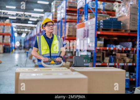 Arbeiter in großen Lagerhäusern verwenden die Transportbox für Palettenhubwagen, um sie in Regalen zu verteilen Stockfoto