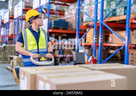 Arbeiter in großen Lagerhäusern verwenden die Transportbox für Palettenhubwagen, um sie in Regalen zu verteilen Stockfoto