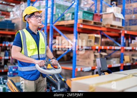 Arbeiter in großen Lagerhäusern verwenden die Transportbox für Palettenhubwagen, um sie in Regalen zu verteilen Stockfoto