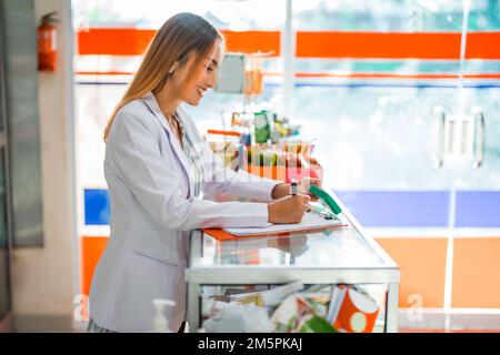 Apothekerin, die mit Stift und Klemmbrett schreibt, in der Apotheke Stockfoto