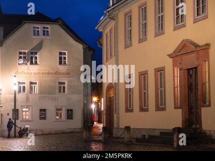 Weimar, Deutschland. 22. Dezember 2022. Das Goethehaus (r) am Abend beim Frauenplan, links ist das Gasthaus zum weißen Schwan. Johann Wolfgang von Goethe lebte im Goethehaus, das 1709 erbaut wurde, für fast 50 Jahre bis zu seinem Tod. Das Gebäude der Klassik Stiftung Weimar, das zum UNESCO-Weltkulturerbe gehört, ist Teil des Ensembles des Goethe-Nationalmuseums und soll ab 2026 renoviert werden. Kredit: Soeren Stache/dpa/Alamy Live News Stockfoto