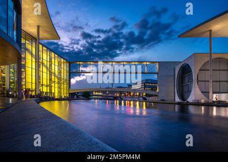 Berlin, Deutschland - Juni 25 2022: Blick auf den Sonnenuntergang im Kanzlerviertel mit Marie Elizabeth Lueders Haus und der Fußgängerbrücke über der Spree. Stockfoto