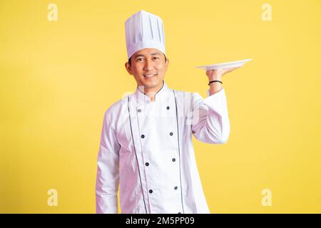 Ein gutaussehender Koch, der einen Servierteller hält, der auf einem isolierten Hintergrund steht Stockfoto
