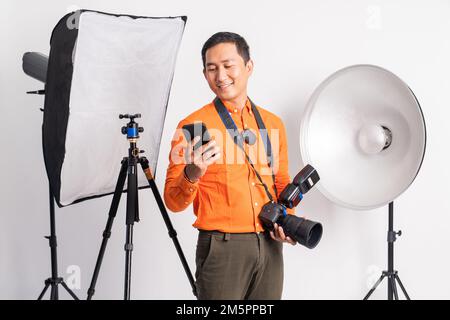 Männlicher Vlogger, der mit dem Handy steht, während er die Kamera hält Stockfoto