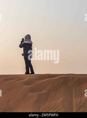Person, die Schutzkleidung trägt und durch die Wüste geht Stockfoto